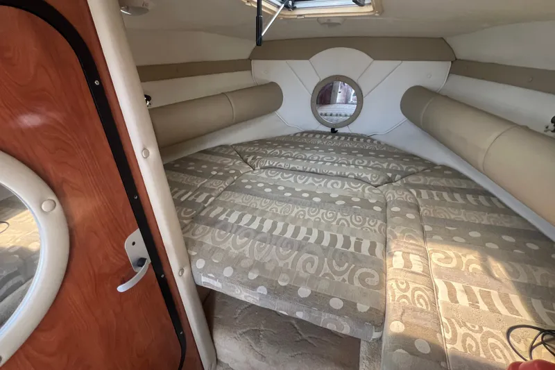 Slide: The Image of Interior cabin of 2004 Rinker 282 Captiva Bowrider with patterned bedding and circular window. - 25