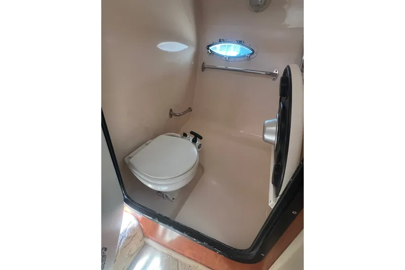 Slide: The Image of 2004 Rinker 282 Captiva Bowrider boat bathroom with toilet and porthole window. - 43
