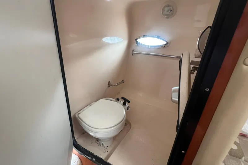 Slide: The Image of 2004 Rinker 282 Captiva Bowrider boat bathroom with toilet and porthole window. - 26