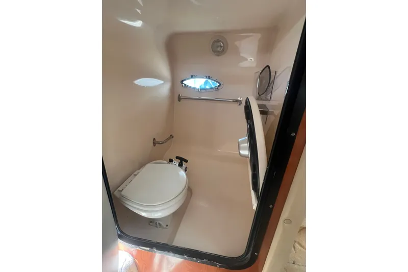 Slide: The Image of 2004 Rinker 282 Captiva Bowrider boat bathroom with toilet and porthole window. - 45