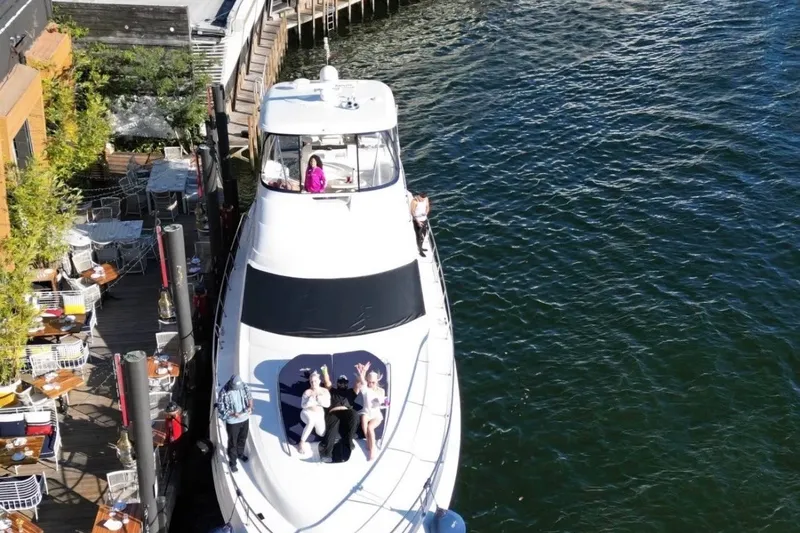 Slide: The Image of 2006 Searay Sedan Bridge yacht docked, people relaxing on deck, waterfront dining nearby. - 4