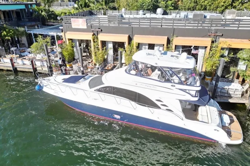 Slide: The Image of 2006 Searay Sedan Bridge yacht docked by waterfront restaurant. - 0