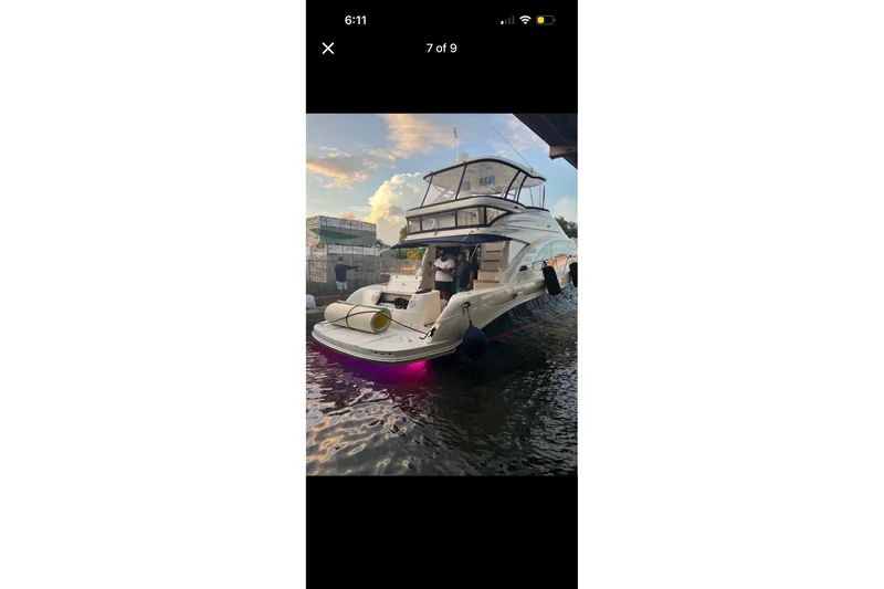 Slide: The Image of 2006 Searay Sedan Bridge yacht docked at sunset with vibrant underwater lights. - 2