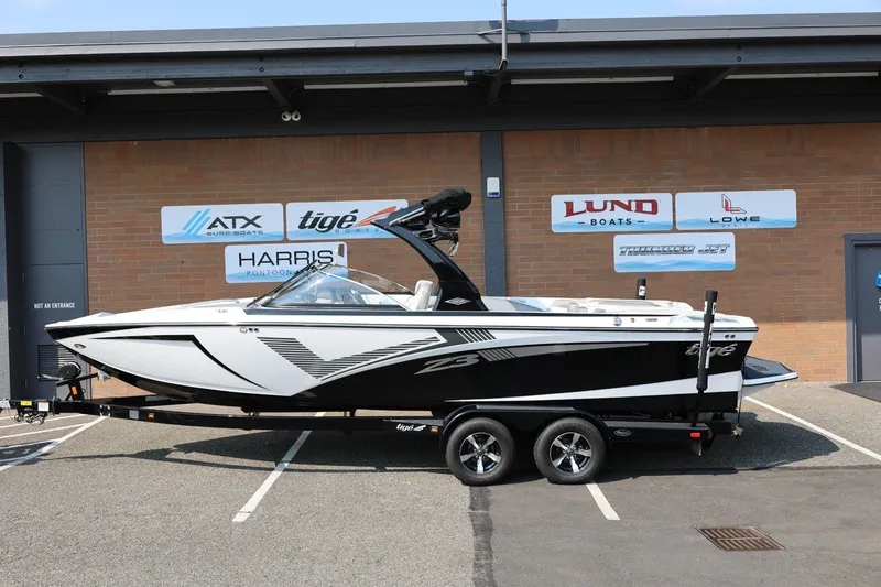 The Image of 2013 Tigé Z3 boat on trailer, parked outside dealership with branded signage. - 1