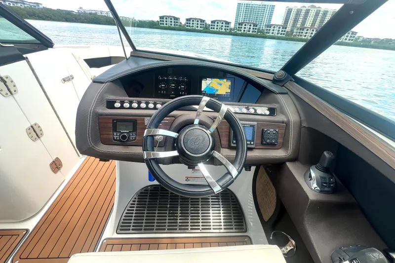 Slide: The Image of 2017 Cobalt R30 boat dashboard with steering wheel, navigation screen, and controls on a sunny day. - 2