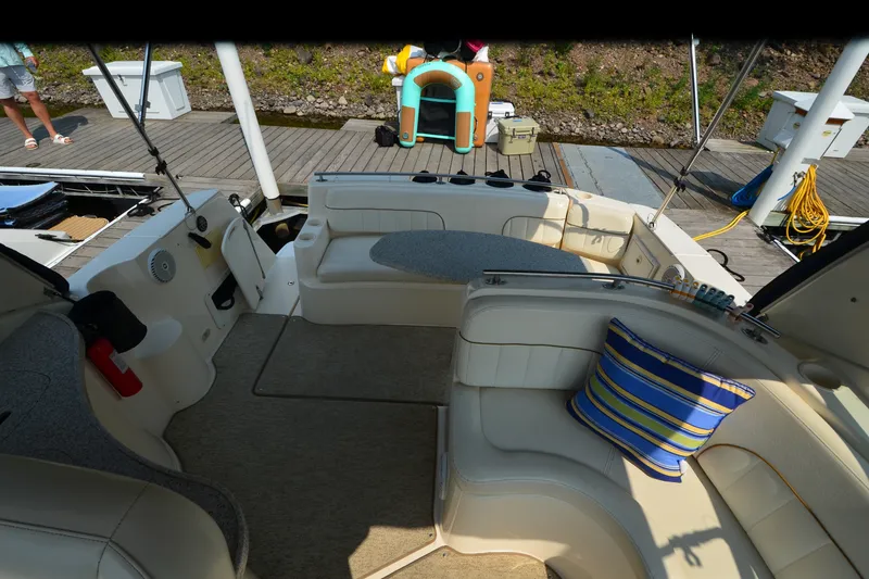 Slide: The Image of 2002 Rinker Fiesta Vee 310 boat interior with seating, striped cushion, and dockside view. - 15