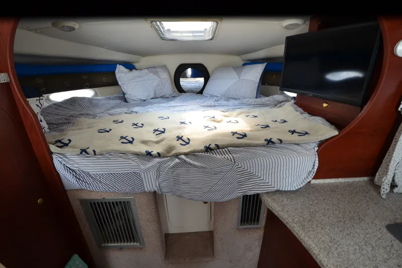 Slide: The Image of Cozy cabin interior of 2002 Rinker Fiesta Vee 310 with nautical-themed bedding. - 19