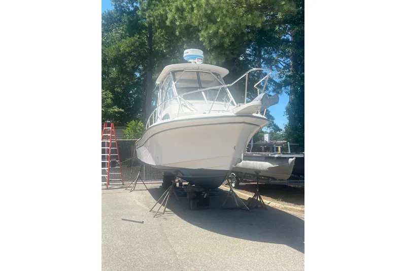 Slide: The Image of 2003 Grady-White Sailfish 282 boat on dry dock, surrounded by trees and equipment. - 1