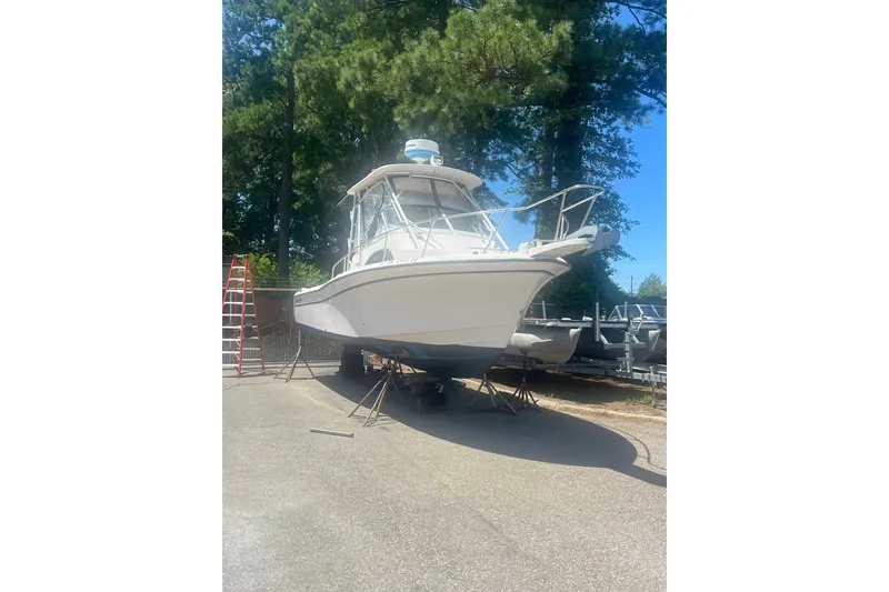 Slide: The Image of 2003 Grady-White Sailfish 282 boat on stands, surrounded by trees and equipment. - 2