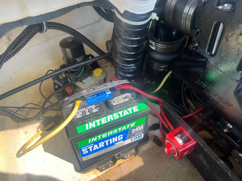 Slide: The Image of An engine compartment with an Interstate battery and various cables and hoses. - 21