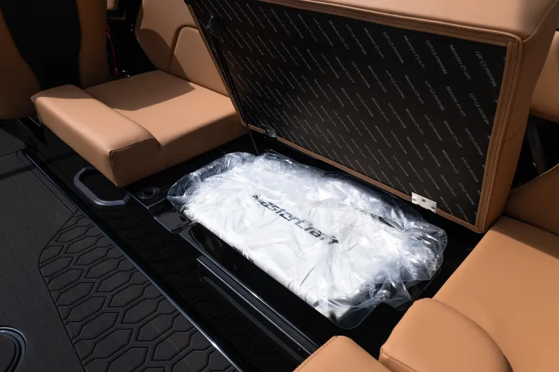 Slide: The Image of 2027 MasterCraft NXT24 boat interior storage with tan seats and branded cover. - 26