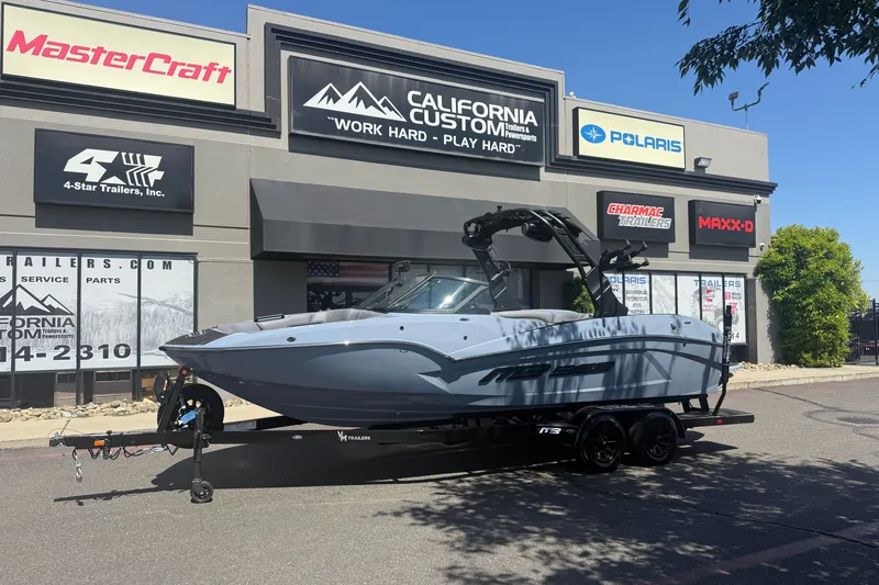 The Image of 2026 MB B52 23 Alpha boat on trailer outside California Custom dealership. - 1