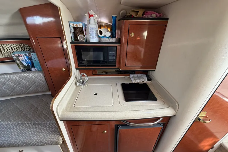 Slide: The Image of 2001 Sea Ray Sundancer 280 cabin kitchen with microwave, sink, and storage cabinets. - 22