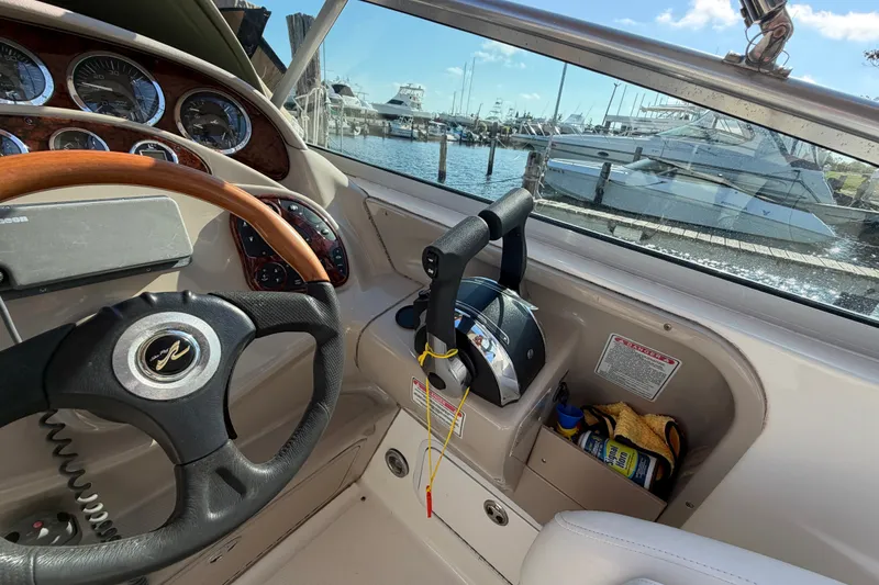 Slide: The Image of 2001 Sea Ray Sundancer 280 helm with steering wheel and throttle controls, docked at marina. - 13