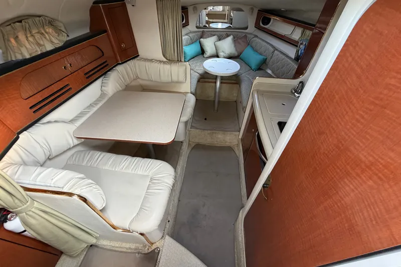Slide: The Image of Interior of 2001 Sea Ray Sundancer 280, featuring cozy seating and a compact dining area. - 16