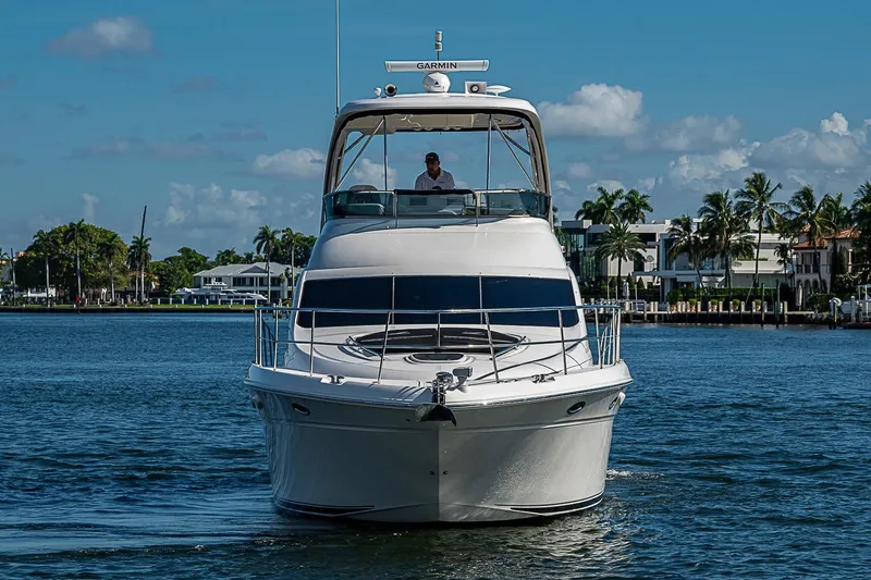 Slide: The Image of 2010 Sea Ray 520 Sedan Bridge yacht cruising on a sunny day, with waterfront homes in the background. - 13