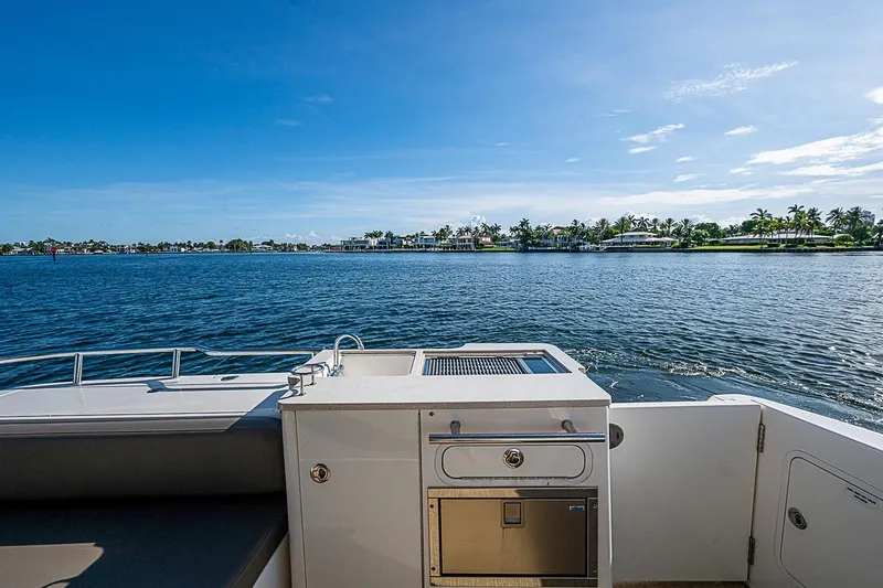 Slide: The Image of 2010 Sea Ray 520 Sedan Bridge yacht with outdoor kitchen, overlooking serene waterfront view. - 28