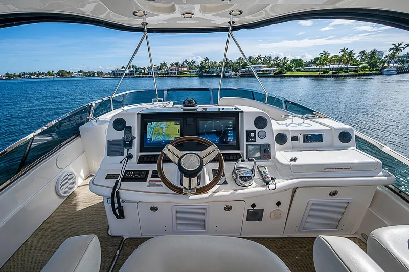 Slide: The Image of 2010 Sea Ray 520 Sedan Bridge helm with navigation screens, overlooking serene waters and palm trees. - 35