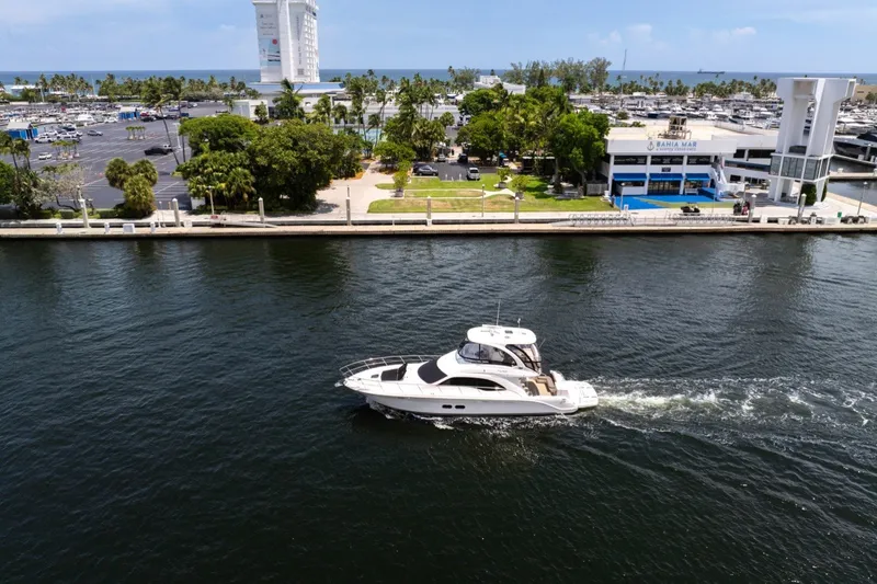 Slide: The Image of 2010 Sea Ray 52 Sedan Bridge yacht cruising near marina with palm trees and buildings. - 79