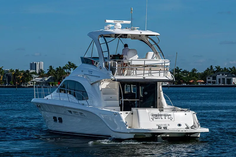 Slide: The Image of 2010 Sea Ray 520 Sedan Bridge yacht cruising on a sunny day, with palm trees in the background. - 9