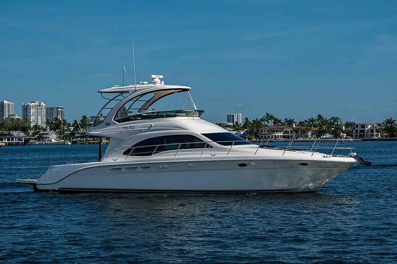 Slide: The Image of 2010 Sea Ray 520 Sedan Bridge yacht cruising on a sunny day near waterfront cityscape. - 10