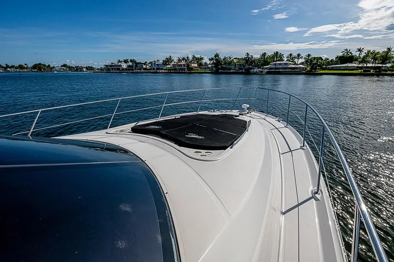 Slide: The Image of 2010 Sea Ray 520 Sedan Bridge yacht cruising on a sunny day, with waterfront homes in the background. - 32