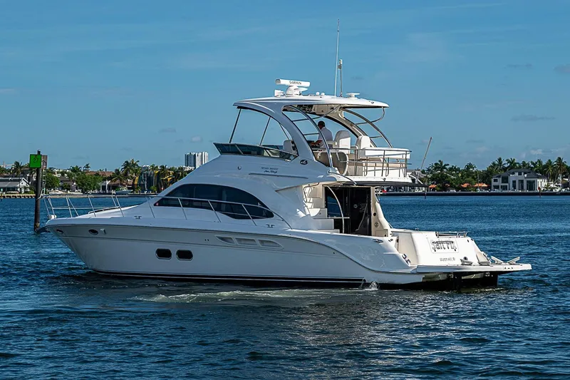 Slide: The Image of 2010 Sea Ray 520 Sedan Bridge yacht cruising on a sunny day, near waterfront homes. - 6