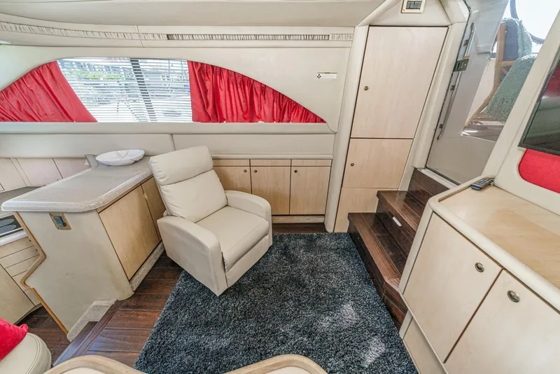 Slide: The Image of Interior of a 1999 Sea Ray 370 Aft Cabin with beige armchair and red curtains. - 30