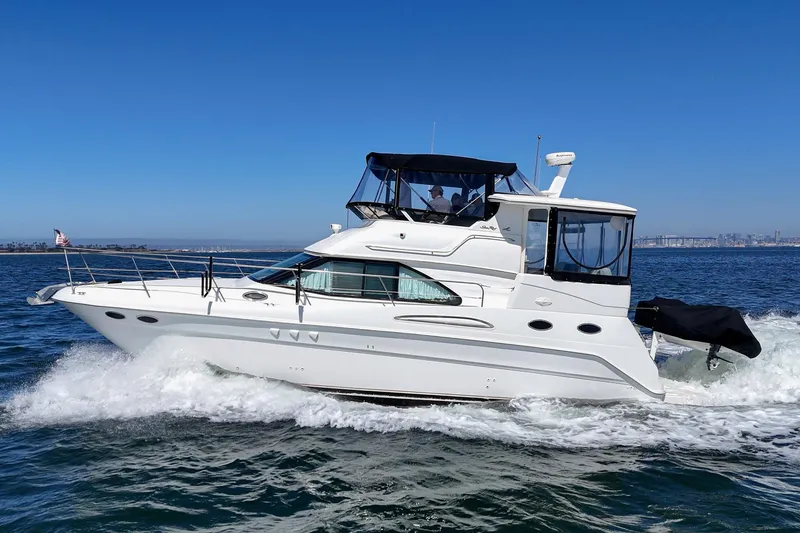 Slide: The Image of A white 1999 Sea Ray 370 Aft Cabin cruising on the water. The sky is clear and blue. - 14