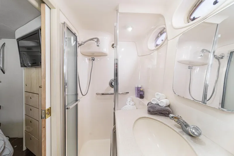 Slide: The Image of The image shows a bathroom in a 1999 Sea Ray 370 Aft Cabin. It features a shower, sink, and mirrors. - 47