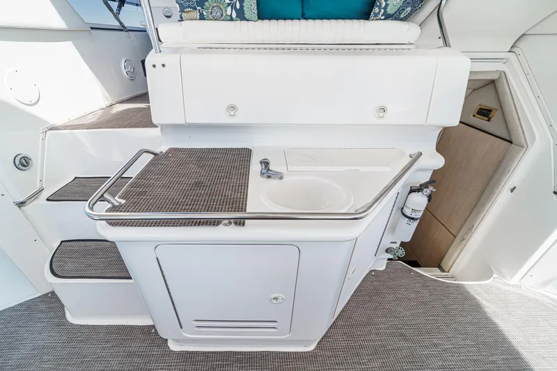 Slide: The Image of The 1999 Sea Ray 370 Aft Cabin features a compact onboard kitchen with a sink and storage. - 20