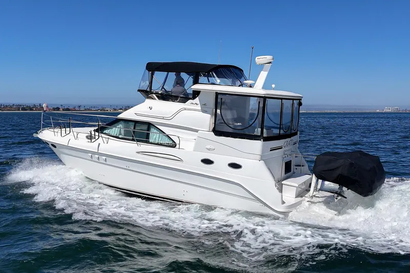 Slide: The Image of A white 1999 Sea Ray 370 Aft Cabin yacht cruising on the water, featuring a black canopy. - 16