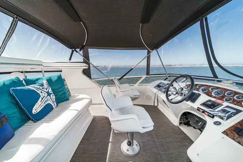 Slide: The Image of The image shows the cockpit of a 1999 Sea Ray 370 Aft Cabin with white seating and blue cushions. - 23