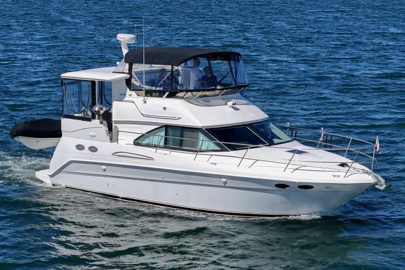 Slide: The Image of A white 1999 Sea Ray 370 Aft Cabin yacht cruising on calm water, featuring a covered upper deck. - 3