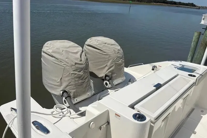 Slide: The Image of 2025 Pursuit S 328 Sport boat with covered dual outboard motors docked by the water. - 33