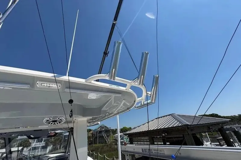 Slide: The Image of 2025 Pursuit S 328 Sport boat with rod holders under clear blue sky. - 24