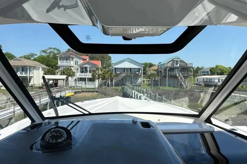 Slide: The Image of View from 2025 Pursuit S 328 Sport boat cockpit, overlooking waterfront homes and docks. - 19