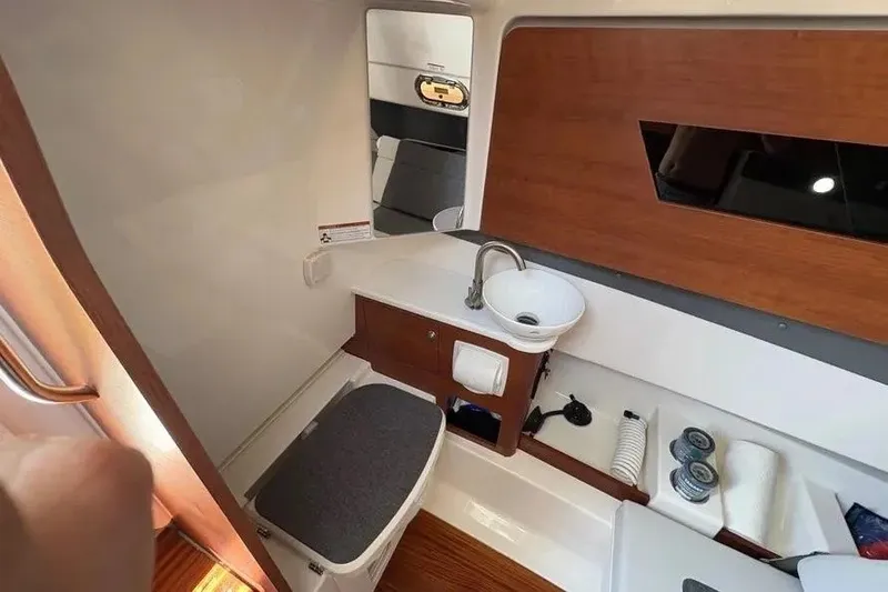Slide: The Image of 2025 Pursuit S 328 Sport boat interior with sink, storage, and wooden accents. - 22