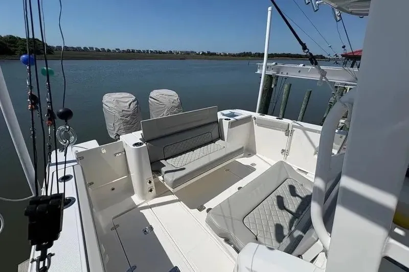 Slide: The Image of 2025 Pursuit S 328 Sport boat interior with seating, docked by a calm river. - 28