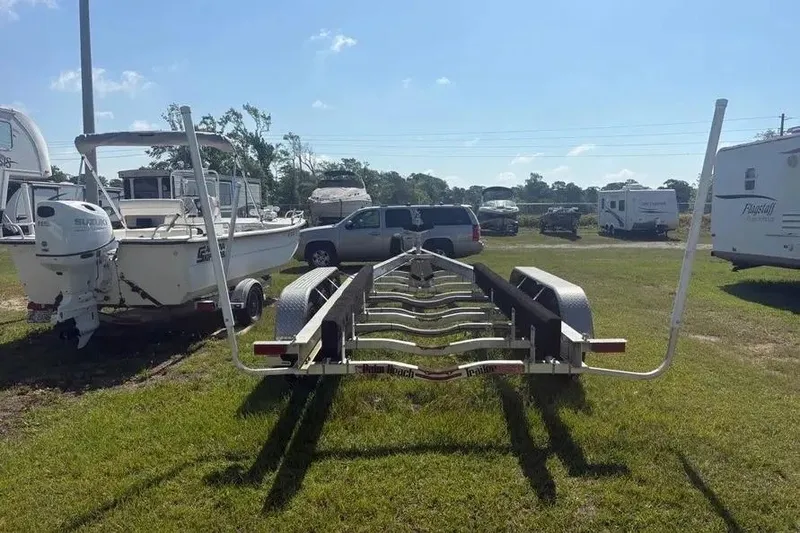 Slide: The Image of Trailer for 2025 Pursuit S 328 Sport boat parked on grass with vehicles nearby. - 40