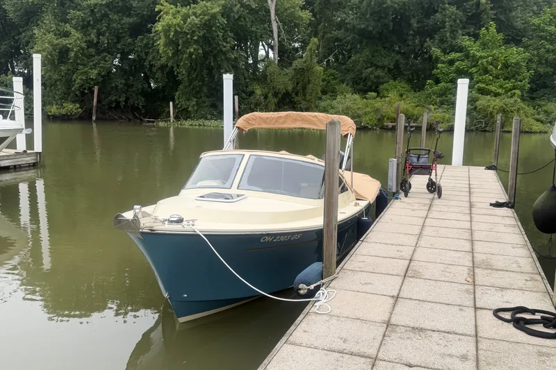 Slide: The Image of 2018 Vanquish Bristol Harbor 23 docked by a lush, green shoreline. - 2