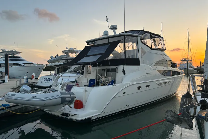 Slide: The Image of 2004 Meridian 459 Motoryacht docked at sunset, featuring sleek design and inflatable dinghy. - 36