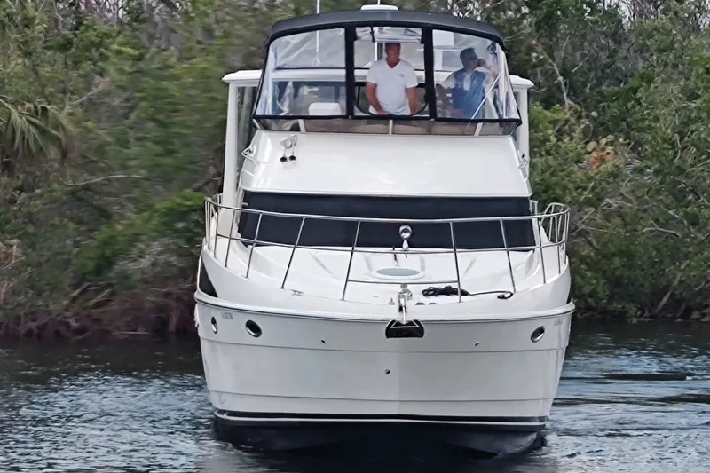Slide: The Image of 2004 Meridian 459 Motoryacht cruising on a calm waterway, surrounded by lush greenery. - 43