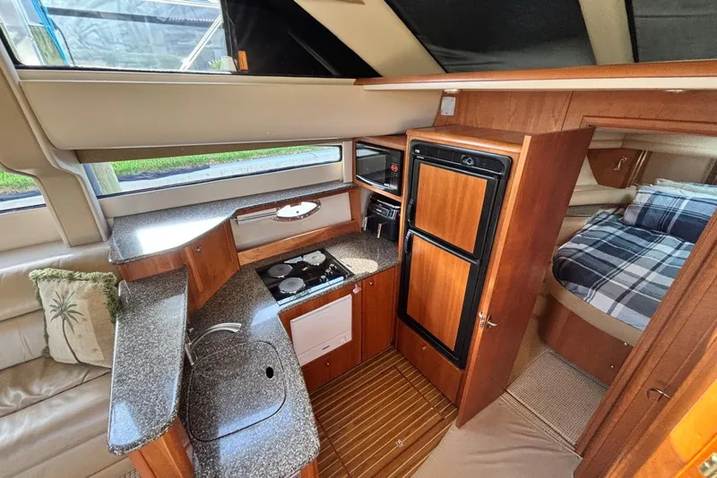 Slide: The Image of 2004 Meridian 459 Motoryacht interior with kitchen, sink, stove, fridge, and cozy sleeping area. - 6