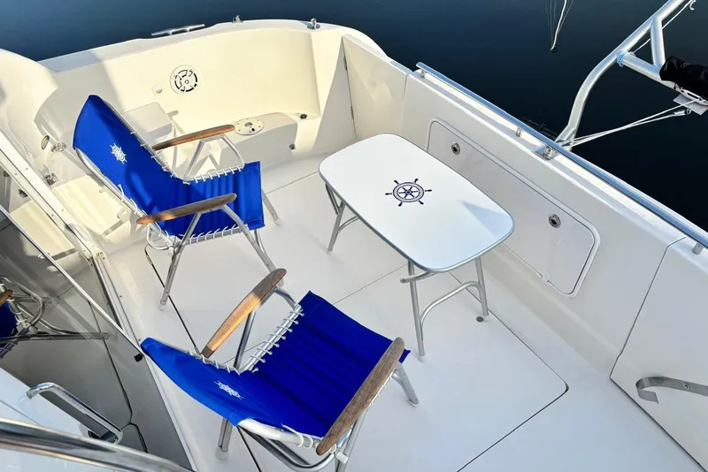 Slide: The Image of 2004 Meridian 459 Motoryacht deck with blue chairs and nautical-themed table. - 31