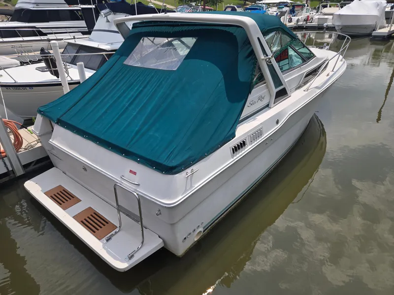 Slide: The Image of A 1987 Sea Ray 300 Weekender in the water, featuring a blue canopy and swim platform. - 1