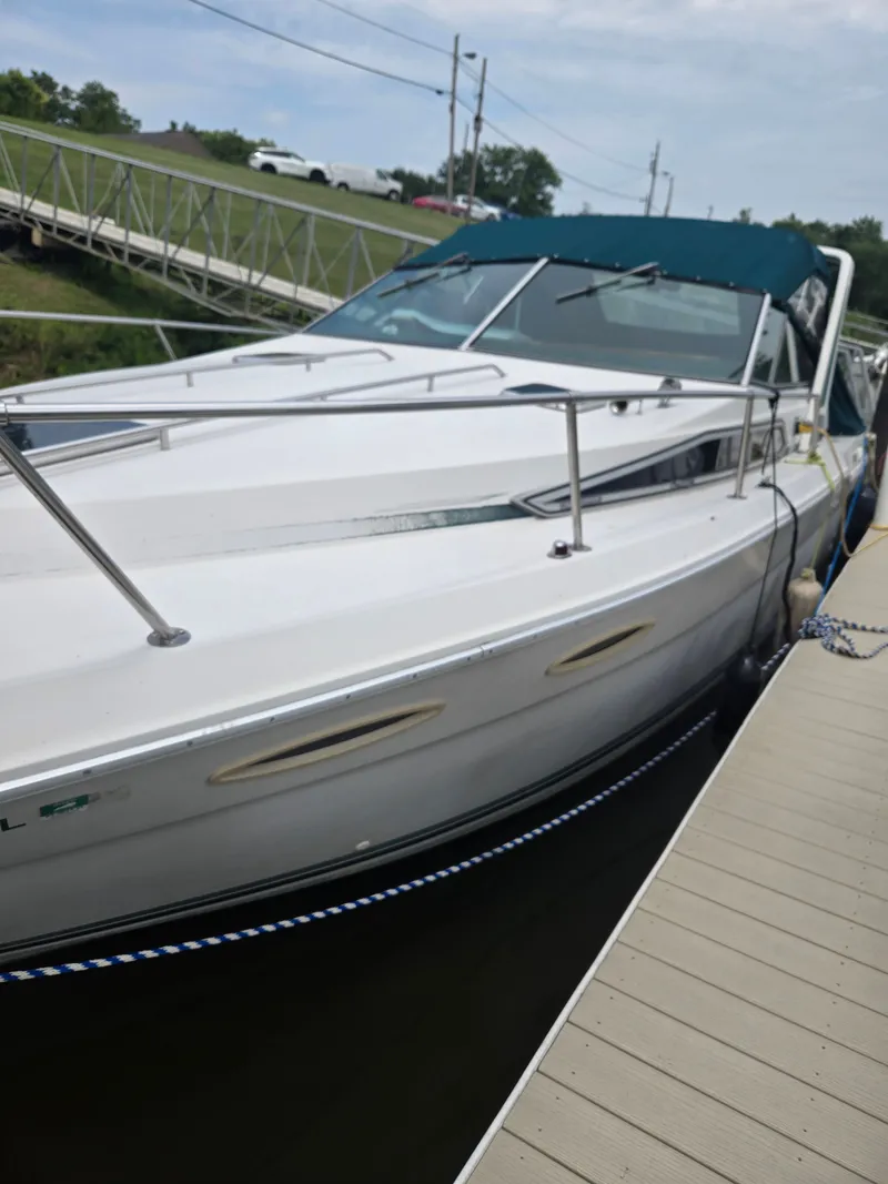 Slide: The Image of A 1987 Sea Ray 300 Weekender docked. It features a blue canopy and stainless steel railings. - 6