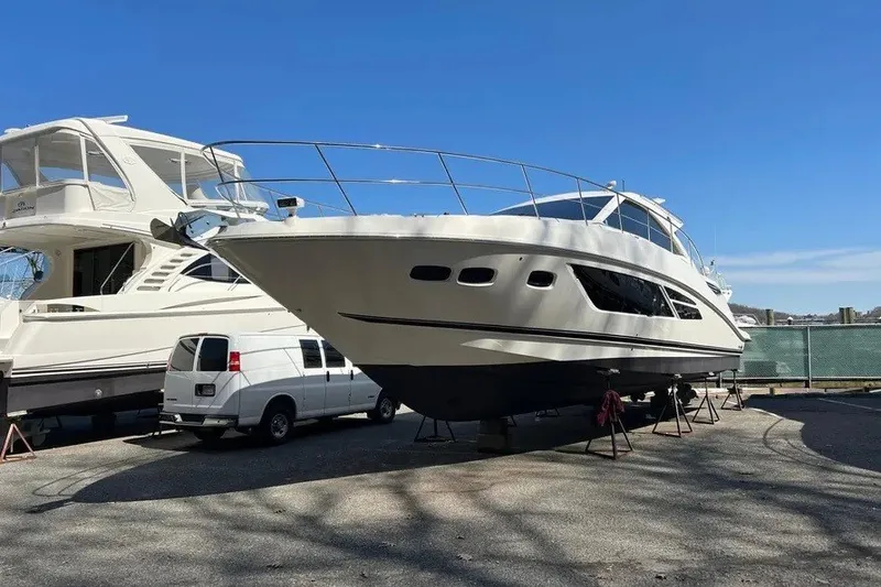 Slide: The Image of 2016 Sea Ray Sundancer 510 yacht on stands, parked beside a white van. - 8