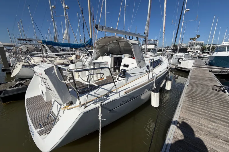 Slide: The Image of 2013 Beneteau Oceanis 370 sailboat docked at marina, surrounded by other vessels. - 2