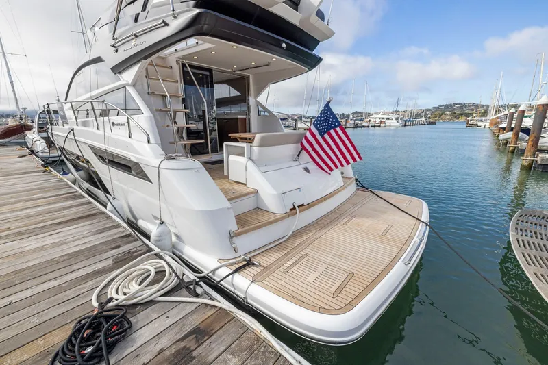 Slide: The Image of 2025 Fairline Squadron 50 yacht docked at marina with American flag displayed. - 82
